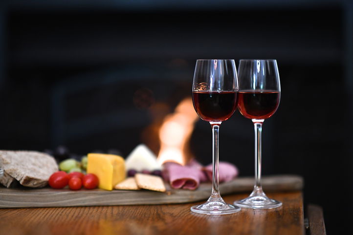 A warm and inviting scene at Bonne Esperance Guest House in Stellenbosch: two sherry glasses, a cheese board, and a roaring fireplace, perfect for winter evenings.