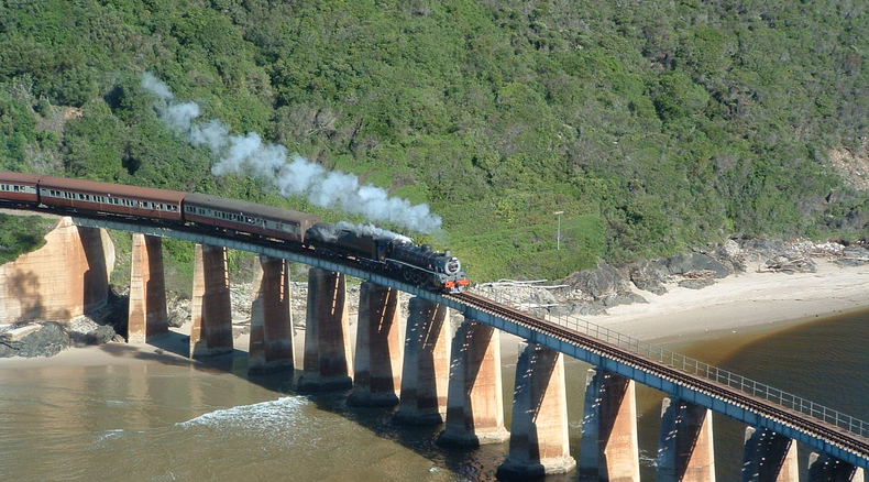 Image: Tim Giddings - public domain. Outeniqua Choo Tjoe on the Kaaimans River Bridge. Photo taken some time before the line was shut down in 2006. Image: Tim Giddings - public domain. Outeniqua Choo Tjoe on the Kaaimans River Bridge. Photo taken some time before the line was shut down in 2006.