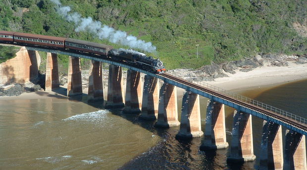 Image: Tim Giddings - public domain. Outeniqua Choo Tjoe on the Kaaimans River Bridge. Photo taken some time before the line was shut down in 2006.