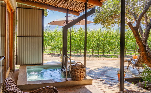 Private wood-fired hot tub on a timber deck overlooking a lush fruit orchard in the Witzenberg Valley
