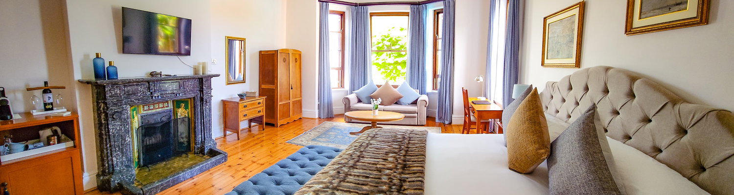 The room features an extra-long king-size bed that can be converted into two single beds on request, along with a comfortable double sleeper couch and an optional baby cot. Ideal for families of up to five sharing.
