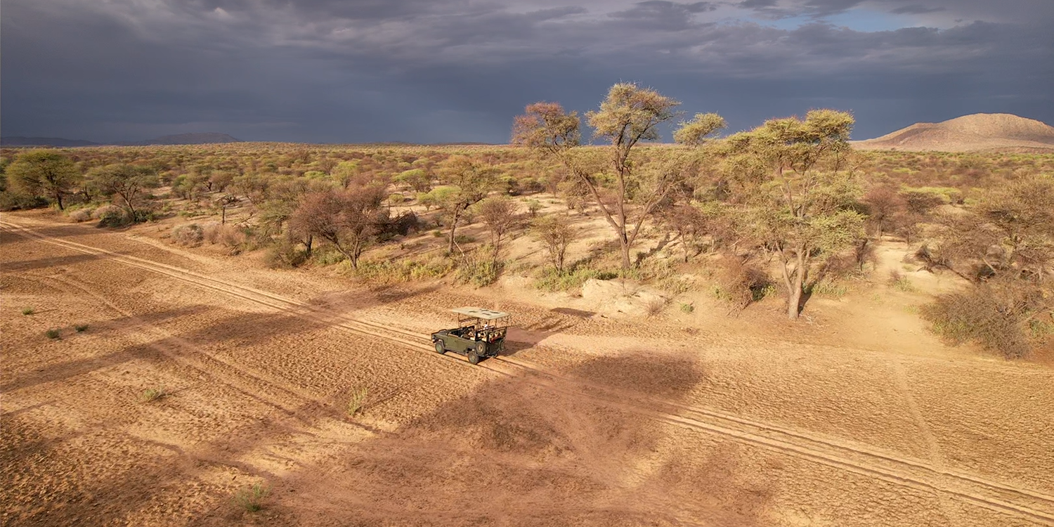 Expansive 9,000-hectare hunting area in Namibia with diverse wildlife, including giraffes, blue wildebeest, and mountain zebras, set against a stunning natural landscape.