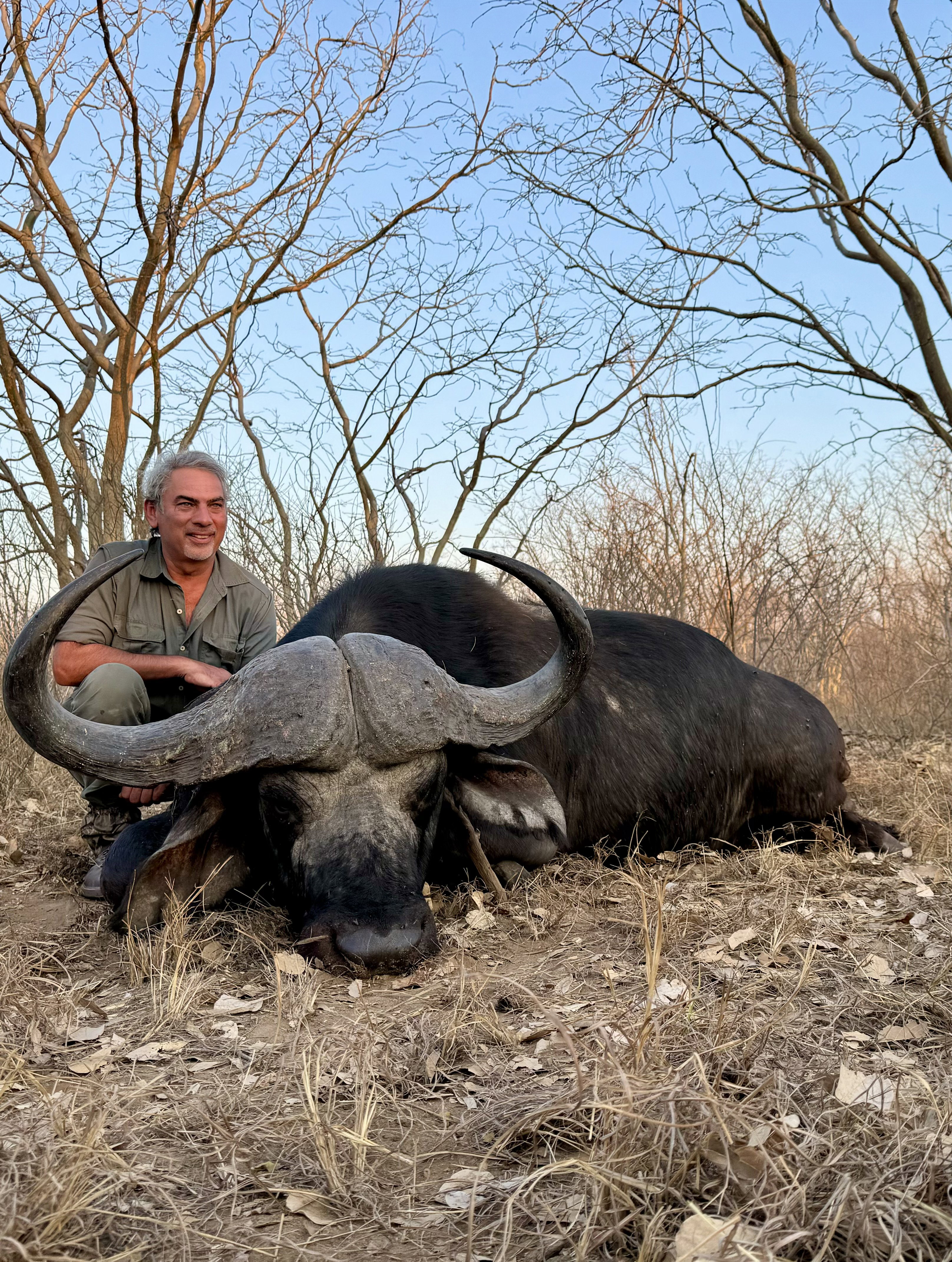 Hunter tracking a large buffalo in Mozambique's 100,000-hectare concession, surrounded by untamed African wilderness.