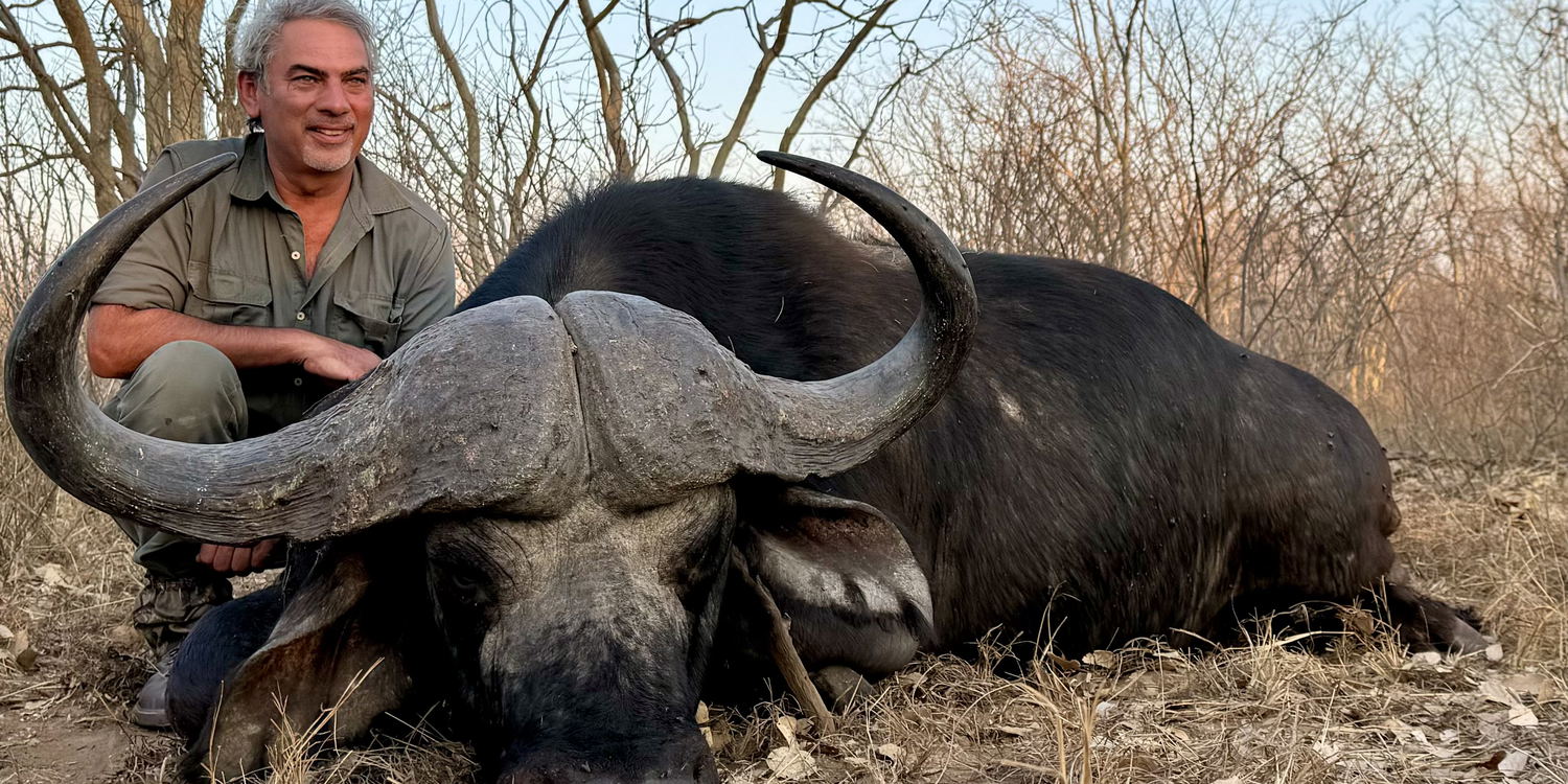 Hunter tracking a large buffalo in Mozambique's 100,000-hectare concession, surrounded by untamed African wilderness.