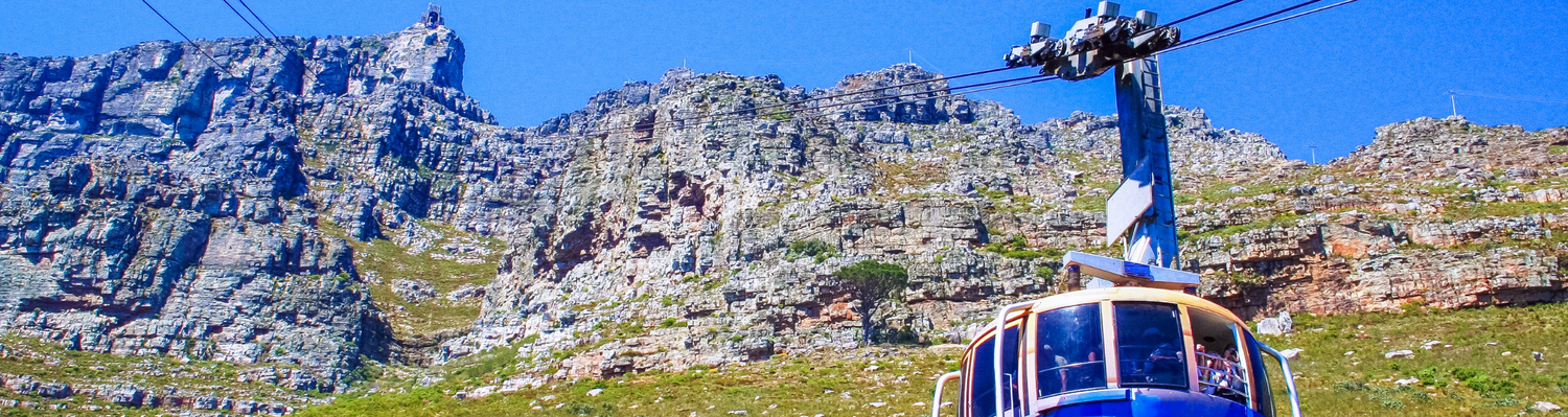 Photograph of tourists in the Table Mountain cable car, in Cape Town, South Africa. The picture has Table Mountain as a back drop