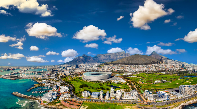 Cape Town's iconic Table Mountain in this breathtaking aerial photograph. The city bowl and the Mother City spread out beneath the majestic Table mountain, their vibrant colors and architectural diversity beautifully juxtaposed against the natural wonder.
