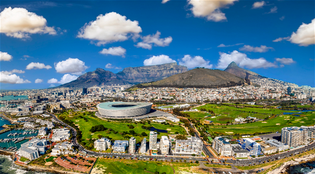 Cape Town's iconic Table Mountain in this breathtaking aerial photograph. The city bowl and the Mother City spread out beneath the majestic Table mountain, their vibrant colors and architectural diversity beautifully juxtaposed against the natural wonder.
