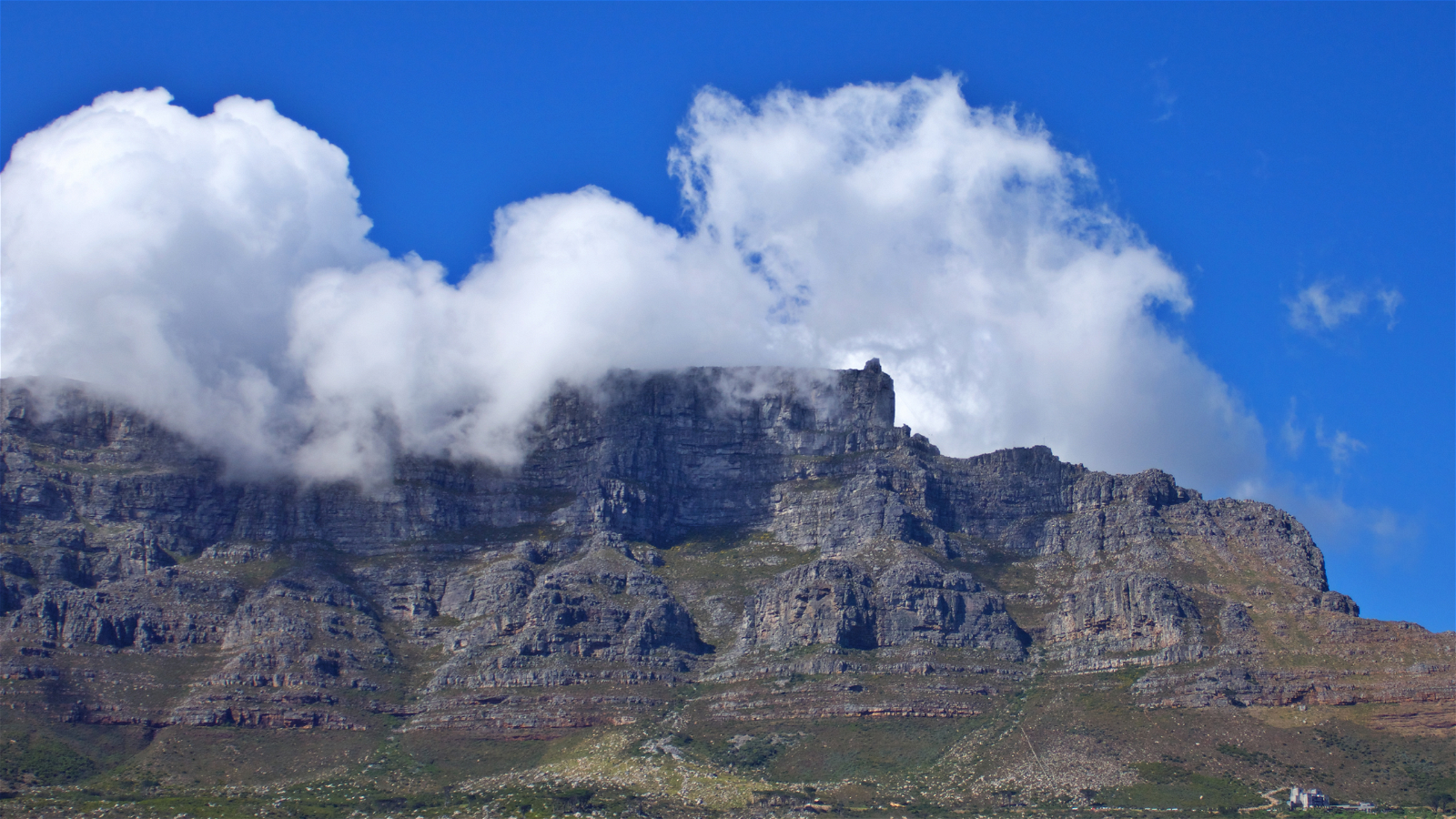 A photograph of Table Mountain taken on a guided excursion captures the awe-inspiring majesty of this iconic natural wonder. The image showcases the mountain's distinctive flat-topped summit, often shrouded in a blanket of mist or clouds, creating an ethereal and otherworldly atmosphere.