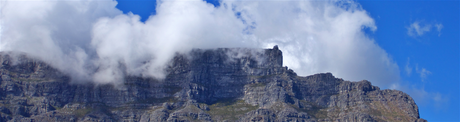 A photograph of Table Mountain taken on a guided excursion captures the awe-inspiring majesty of this iconic natural wonder. The image showcases the mountain's distinctive flat-topped summit, often shrouded in a blanket of mist or clouds, creating an ethereal and otherworldly atmosphere.