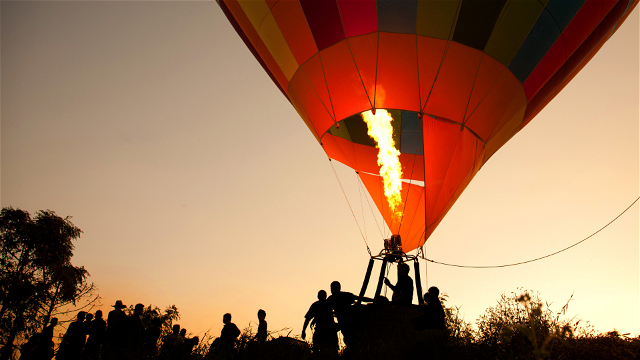 People climbing into a hot air balloon with flames inflating and envelope the balloon at sunrise waiting to launch at the Cape Winelands on a Bucketlist adventure to experience a hot air ballooning at sunrise  