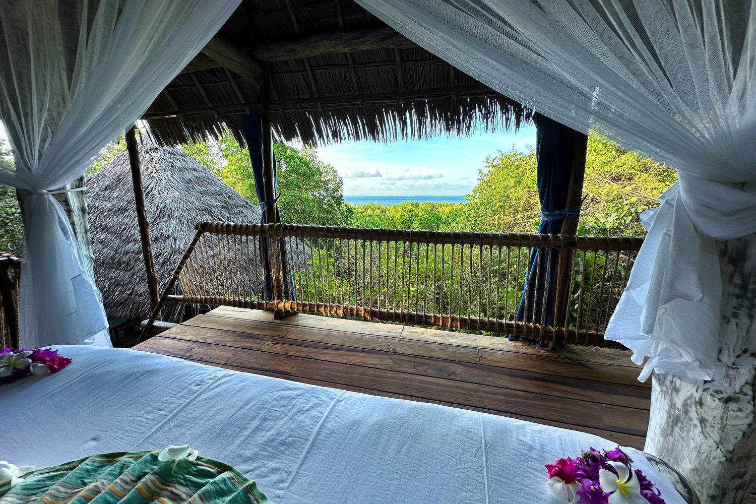 The view from Tatu’s bed, past the mosquito net and across the deck to the treetops and the sea