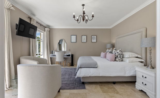 Superior Luxury Suite with elegant décor, king-size bed, cosy seating, and natural light from large windows. Features soft tones, stylish chandelier, modern desk, and serene ambience for a refined stay.