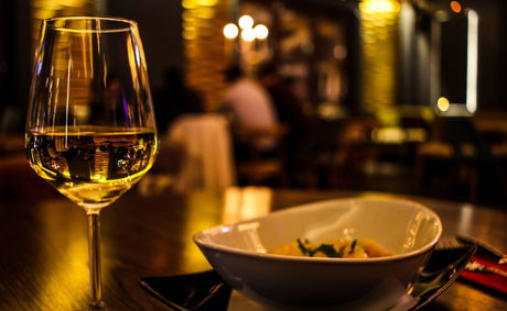 An elegant dining experience featuring a glass of white wine and a gourmet dish, captured in a warmly lit Cape Town restaurant. Ideal for guests of Devonport House seeking memorable culinary outings arranged through our personalised concierge service.