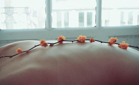 A peaceful spa moment at Devonport House in Constantia, Cape Town, showing a close-up of a guest’s back adorned with delicate orange flowers — symbolising the serene, in-room massage therapy services available for ultimate relaxation during your luxury stay.