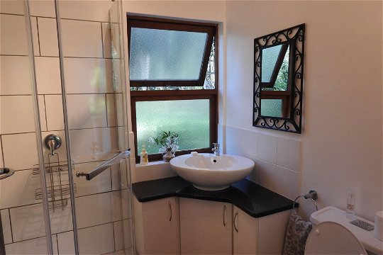 Modern bathroom with corner basin, toilet and shower at Natures Way Farm Cottage