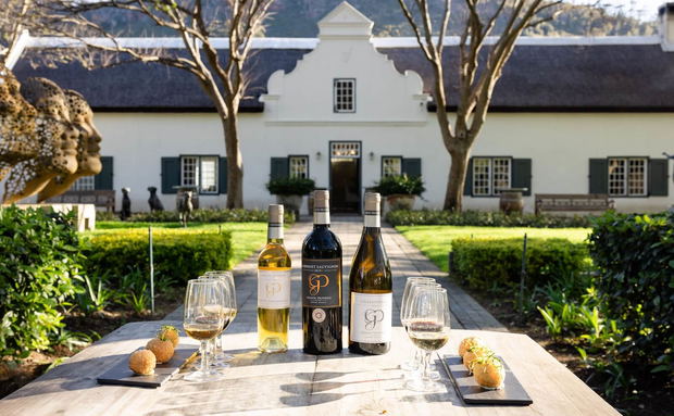 Wine bottles and glasses on a table in a garden courtyard with a historic building in the background Wine bottles and glasses on a table in a garden courtyard with a historic building in the background