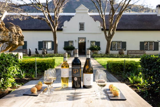 Wine bottles and glasses on a table in a garden courtyard with a historic building in the background Wine bottles and glasses on a table in a garden courtyard with a historic building in the background