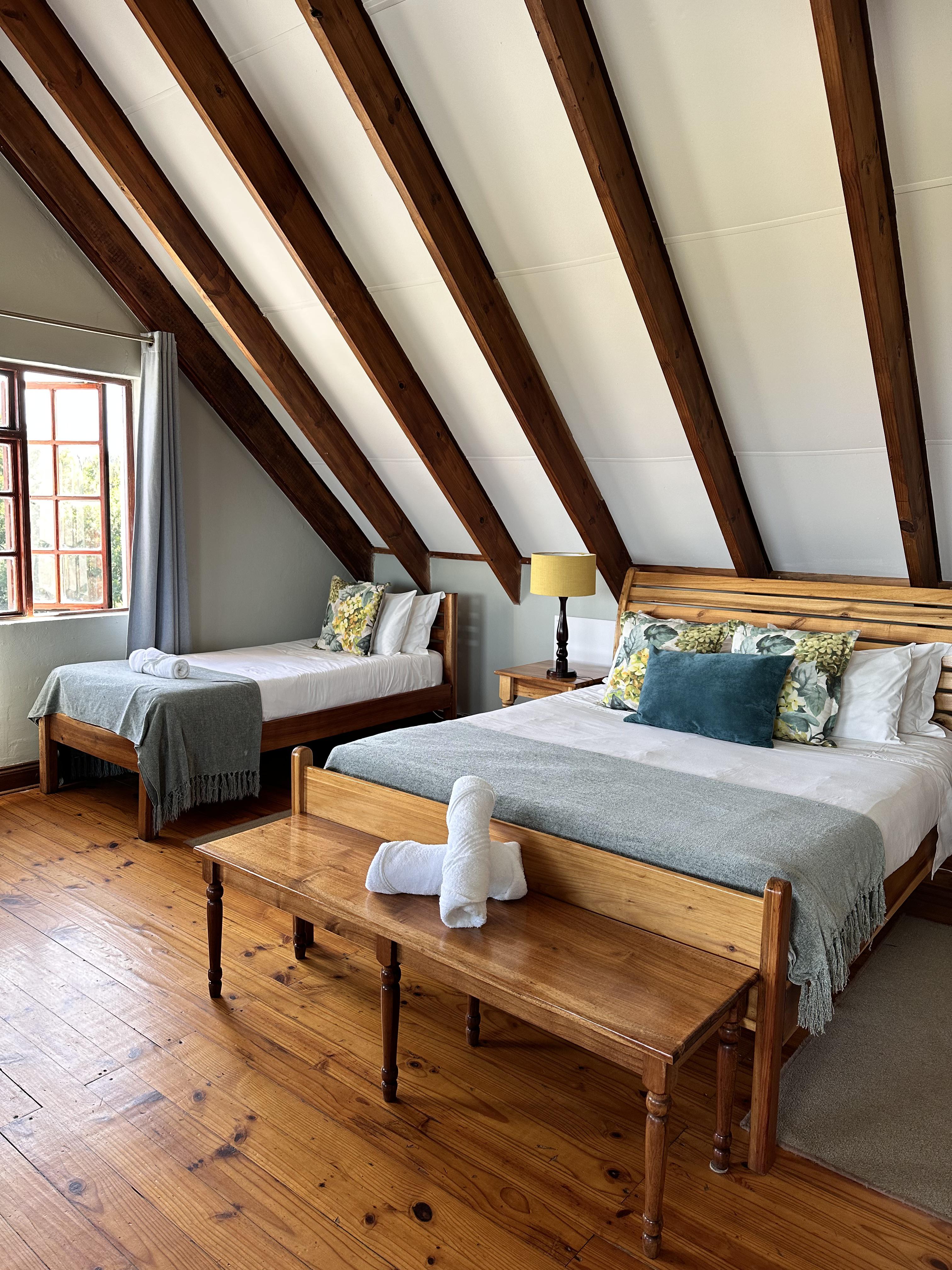a triple en-suite room accommodating three guests with a sitting area and views overlooking the Drakensberg Mountains