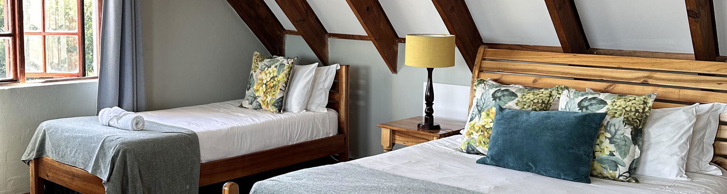 a triple en-suite room accommodating three guests with a sitting area and views overlooking the Drakensberg Mountains