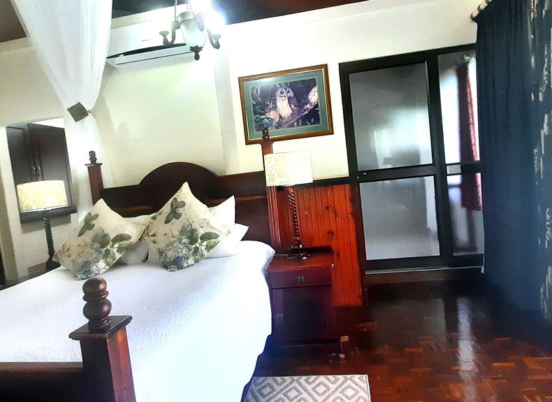 Bedroom St Lucia Wetlands Guesthouse queen bed over looking a swimming pool and sub-tropical garden Bedroom St Lucia Wetlands Guesthouse queen bed over looking a swimming pool and sub-tropical garden