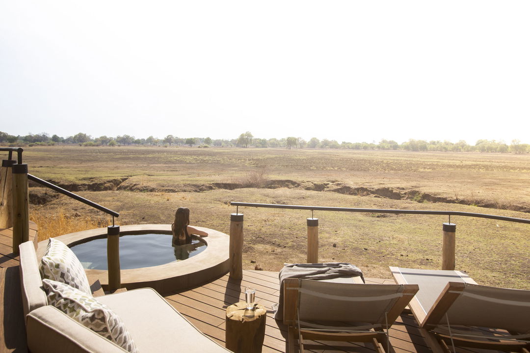lady guest in splash pool on deck of suite overlooking luangwa flood plains Puku Ridge Camp Zambia
