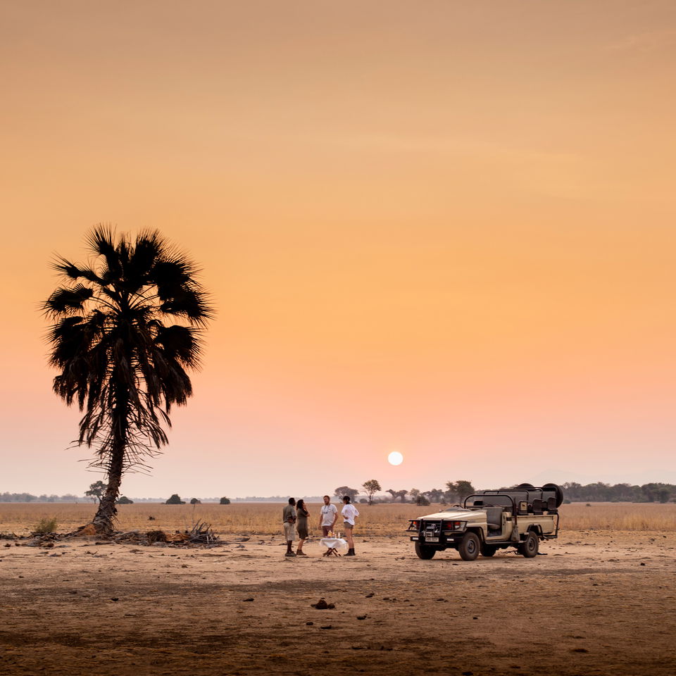 sunset drinks with guide by safari vehicle on plains in Zambia old mondoro camp