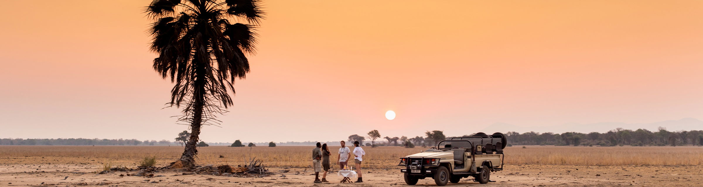 sunset drinks with guide by safari vehicle on plains in Zambia old mondoro camp