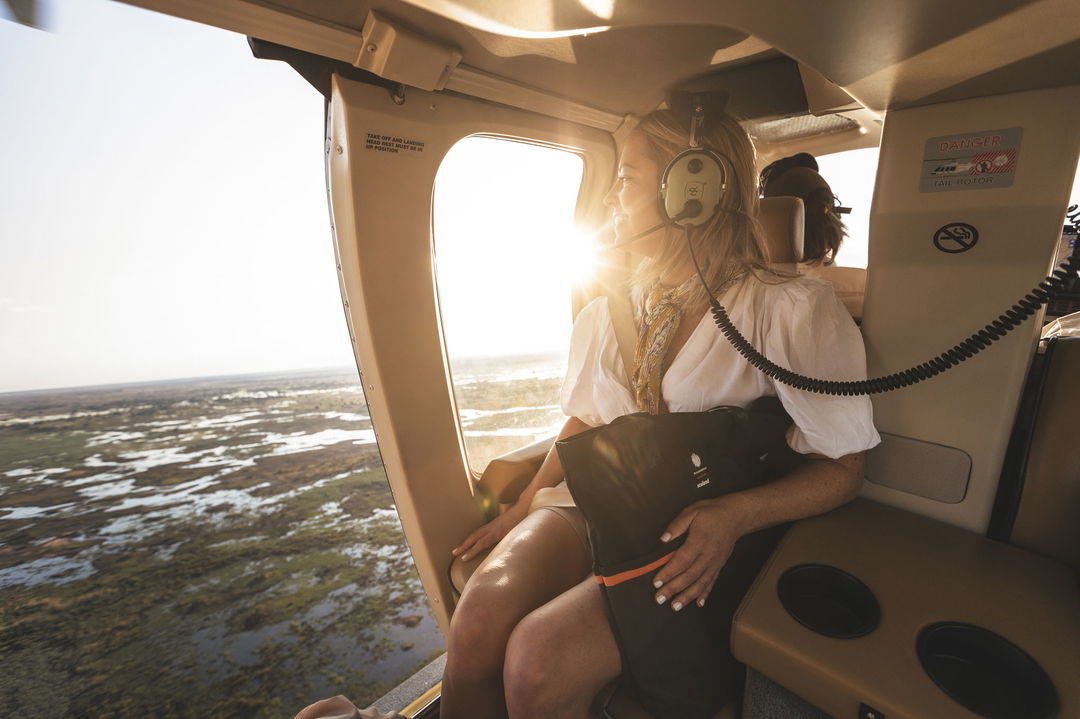 lady in helicopter over Okavango delta with wildlife below at Wilderness Mombo Camp