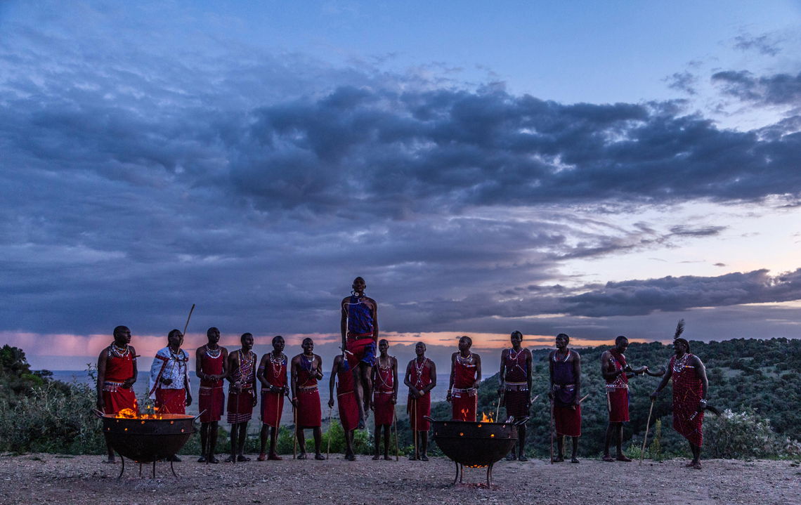 Masai warriors traditional jump dance by fire at sunset of Angama Mara Kenya Masai Mara