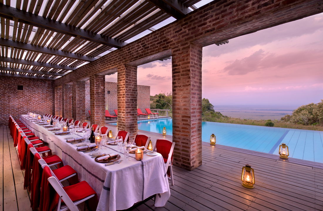 long dinner table setup for supper by pool of Angama Mara Kenya Masai Mara