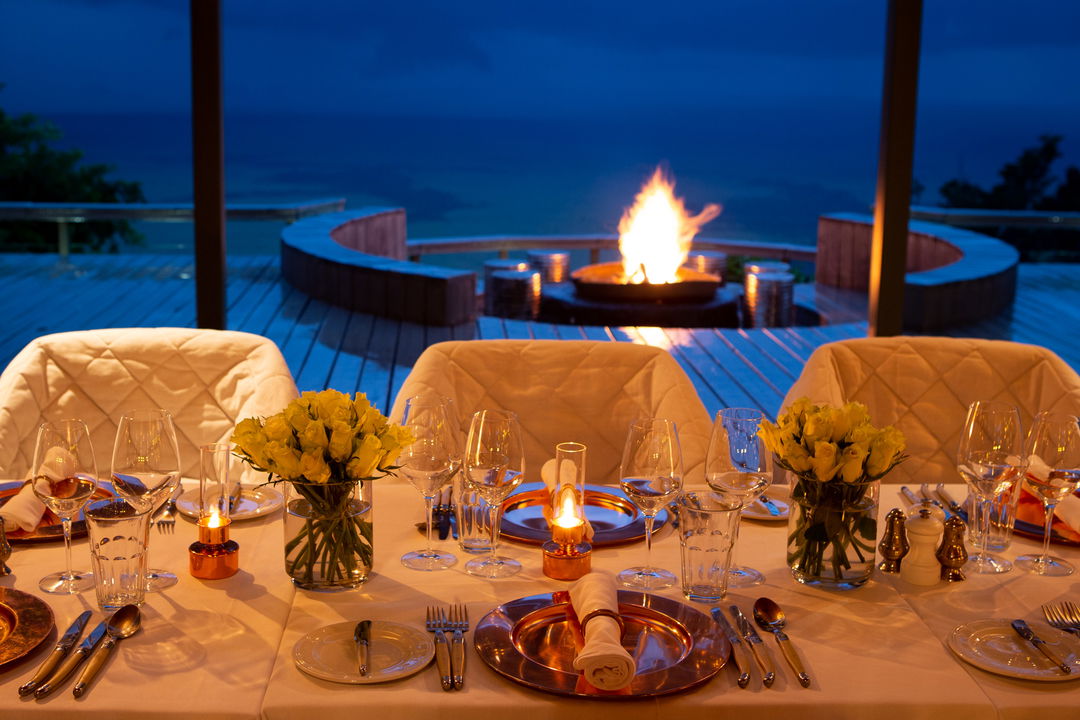 dinner table inside lodge with fire behind at Angama Mara Kenya Masai Mara