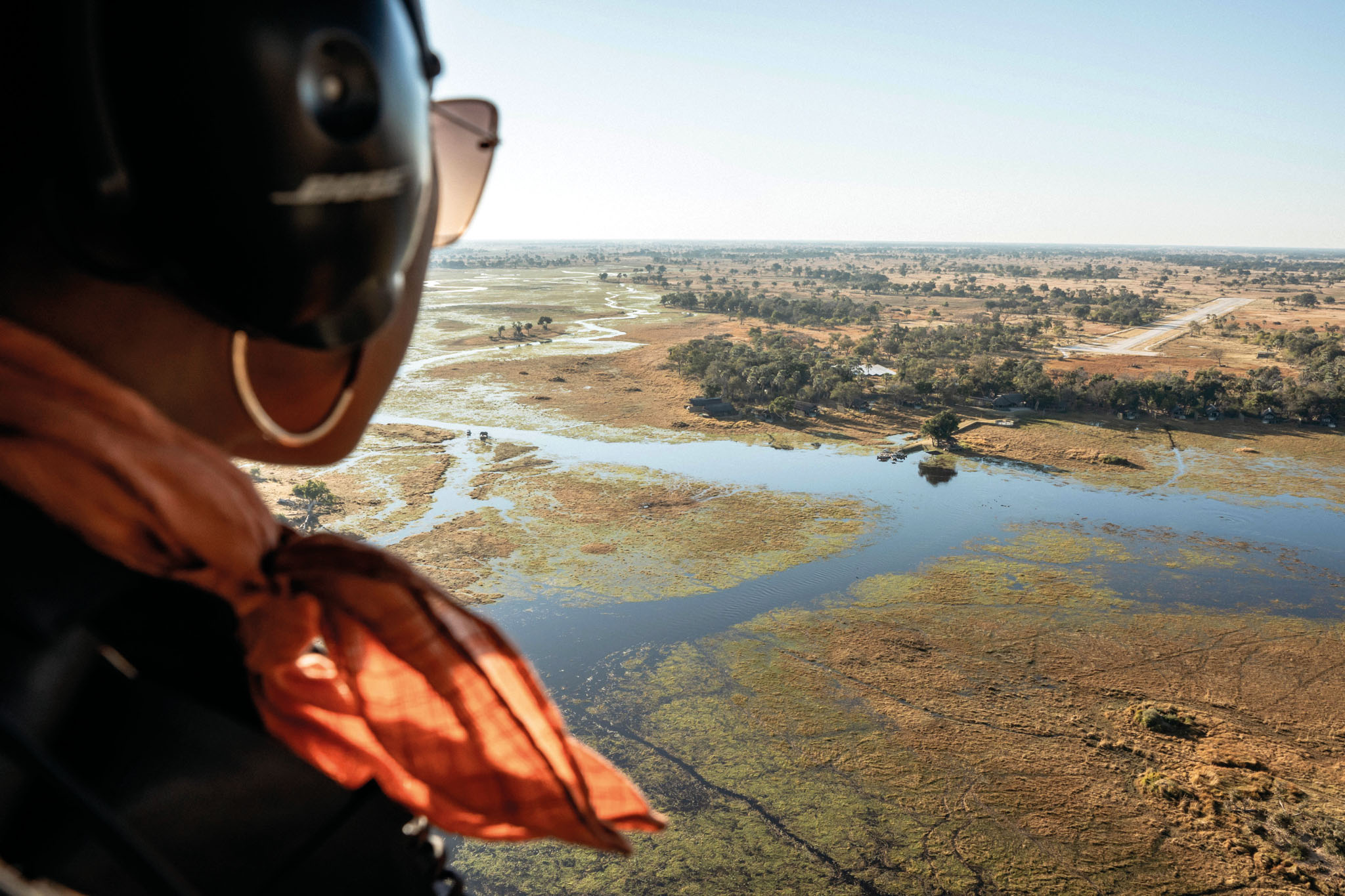 lady guest in helicopter looking down at okavango delta below
