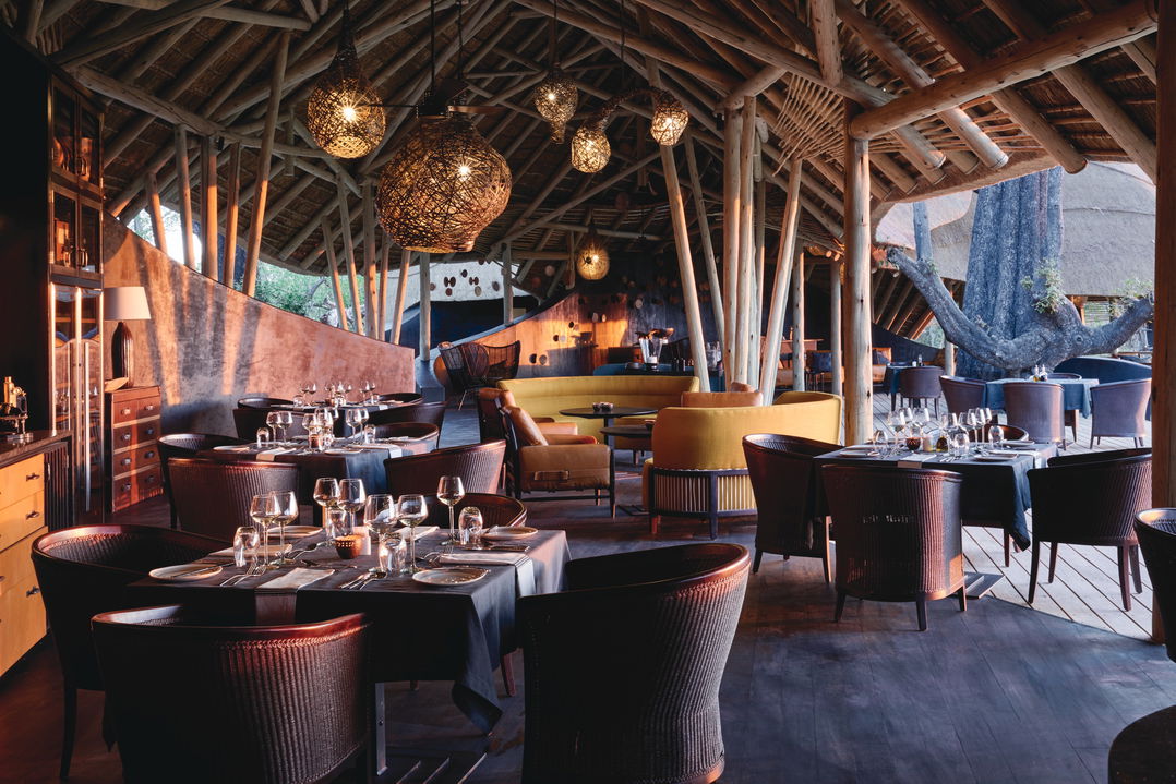 dining area with tables and African art chairs on deck at Eagle island safari lodge Botswana