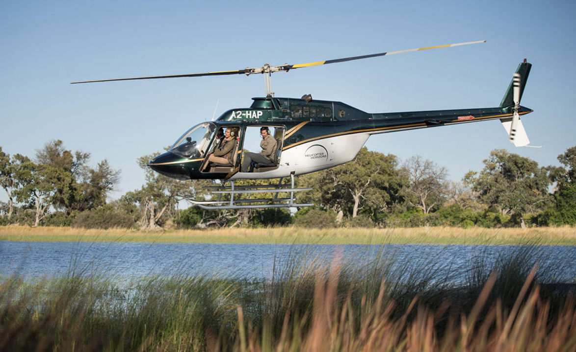 chopper flying low over delta with guests to Belmond Eagle Island Lodge