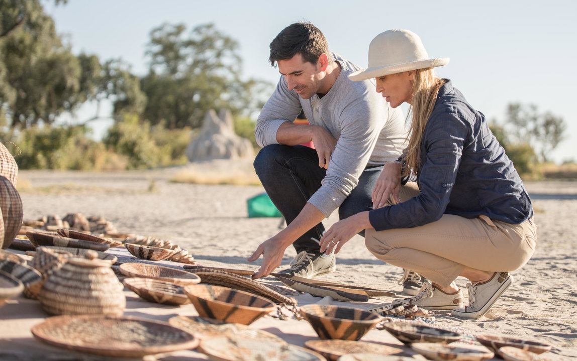 couple looking at curios on ground during a community visit of Belmond Eagle Island Lodge