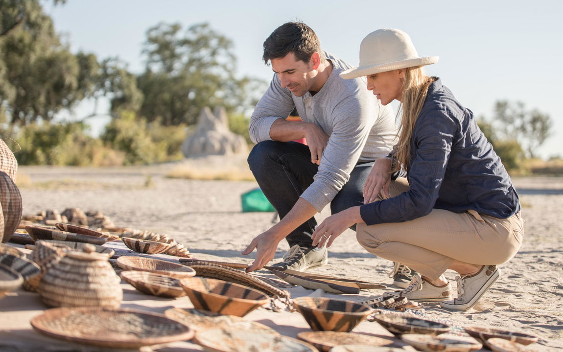 couple looking at curios on ground during a community visit of Belmond Eagle Island Lodge