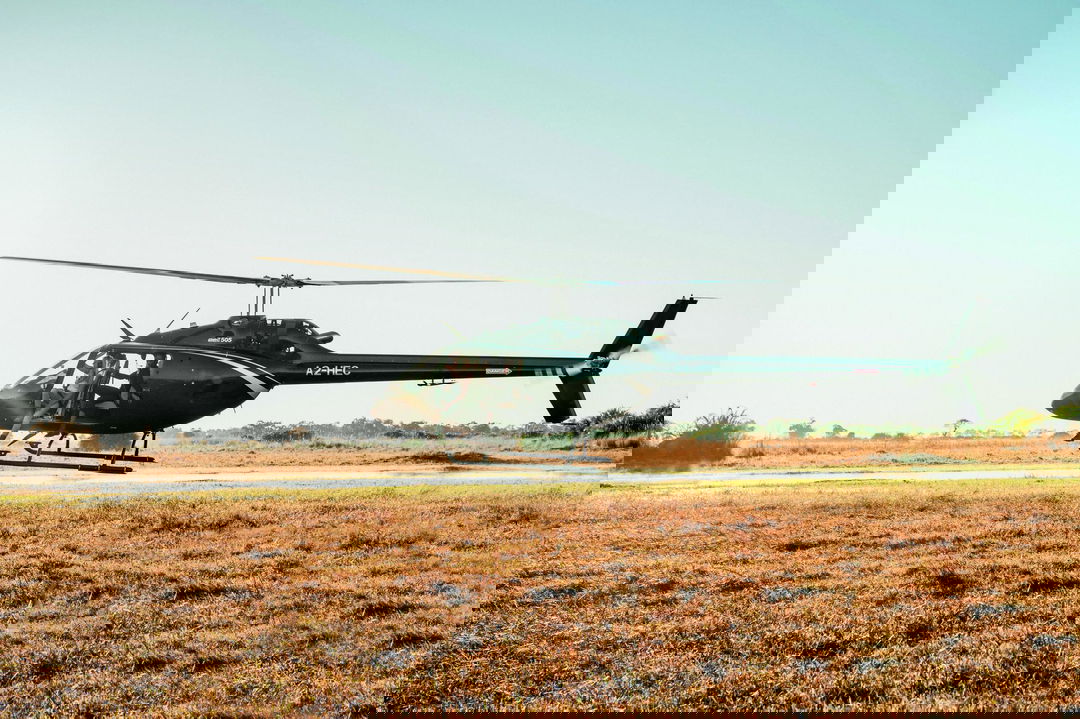 low flying helicopter over Okavango Delta with lady guest partially hanging out at Belmond Eagle Island Lodge