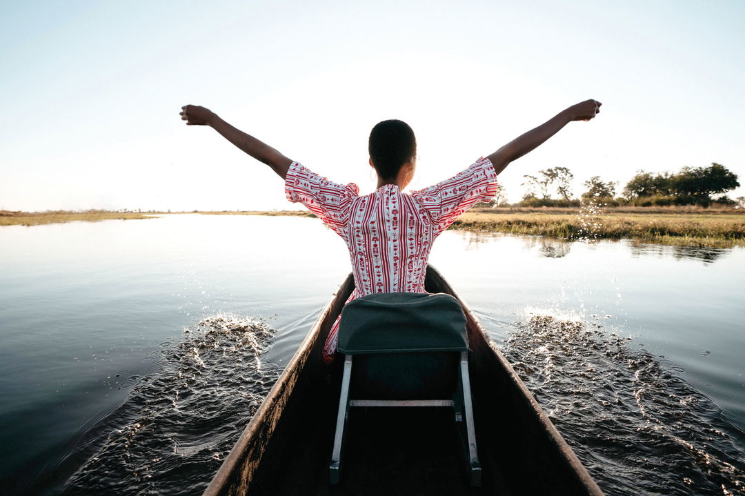 lady guest happy on a mokoro ride on waters of delta by Belmond Eagle Island Lodge