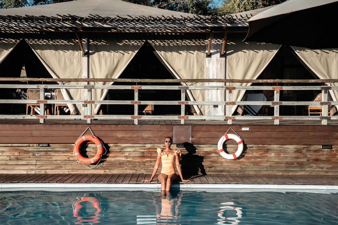 lady guest basking in sun at the main pool of Savute elephant lodge Botswana