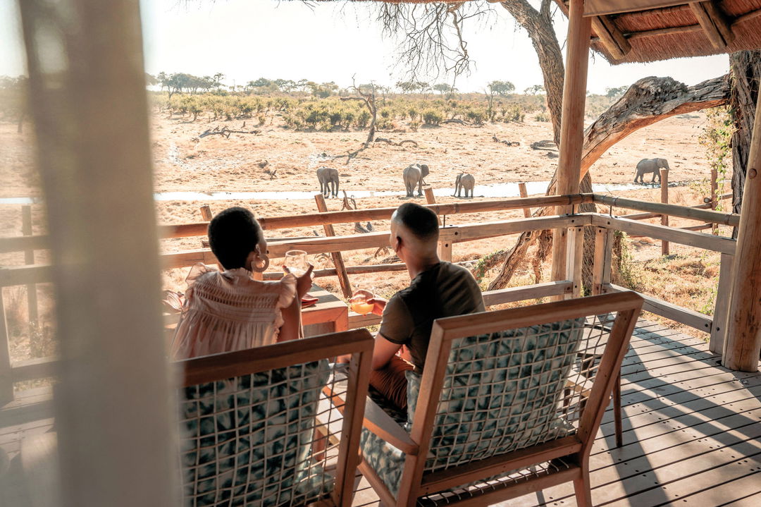 couple in deck of Belmond Safaris Savute Elephant lodge Botswana looking at elephants below