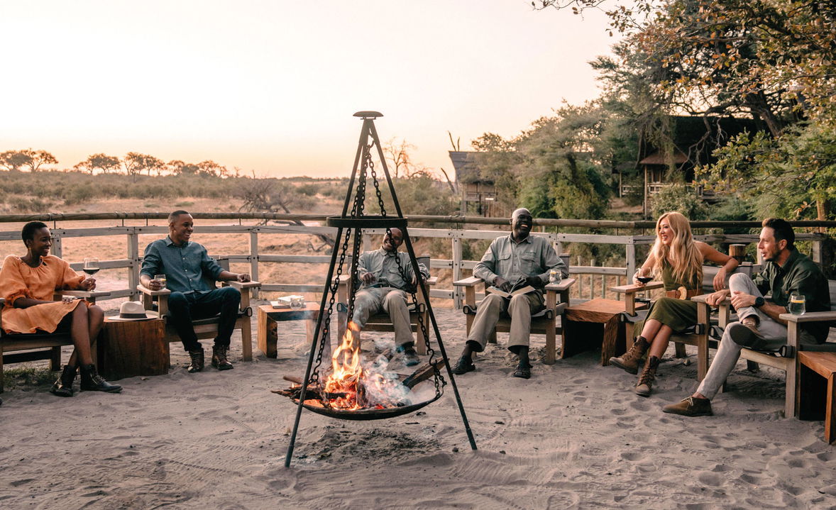 guides sitting in boma by fireplace overlooking Okavango delta in background