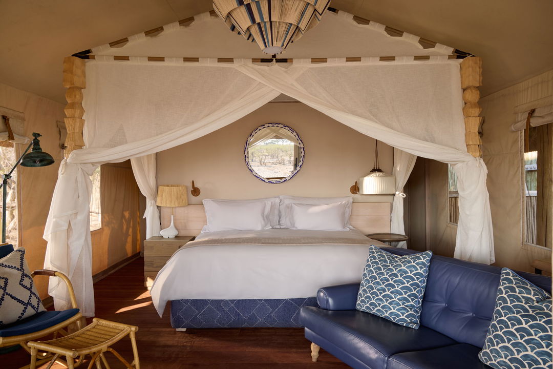 interior view of luxury room with blue four poster bed at Savute elephant lodge Belmond