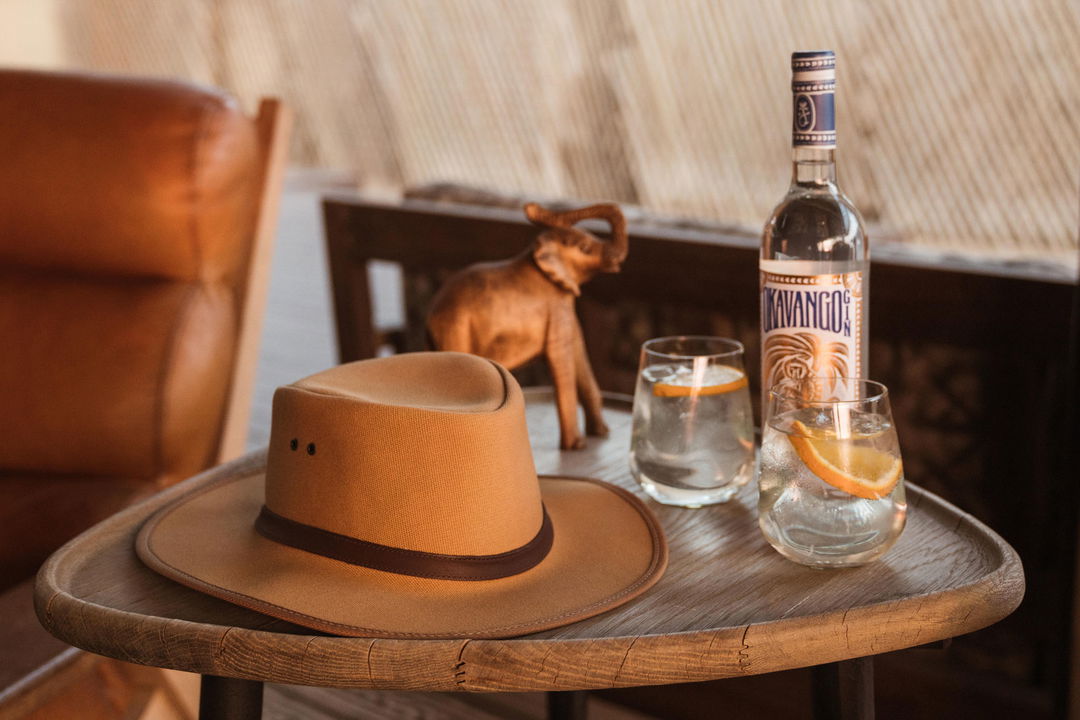 safari hat with drinks on side table at Savute elephant lodge Belmond