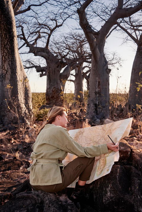 lady guest reading a map under a baobab tree at Savute elephant lodge Botswana