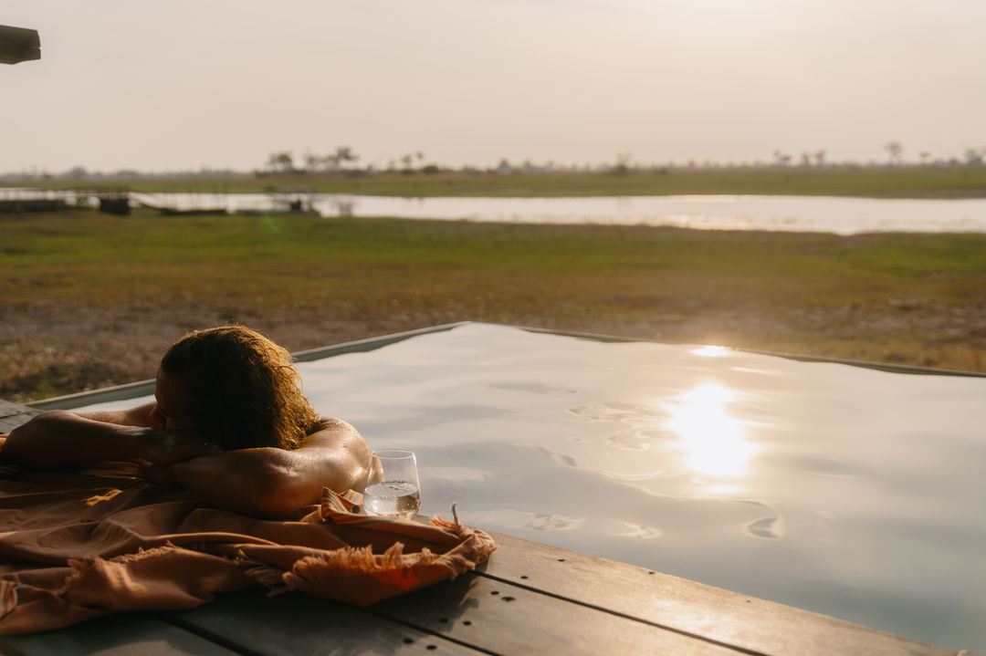 Female guest relaxing in pool with a drink overlooking the Okavango delta waters at eagle island luxury safari lodge by Belmond
