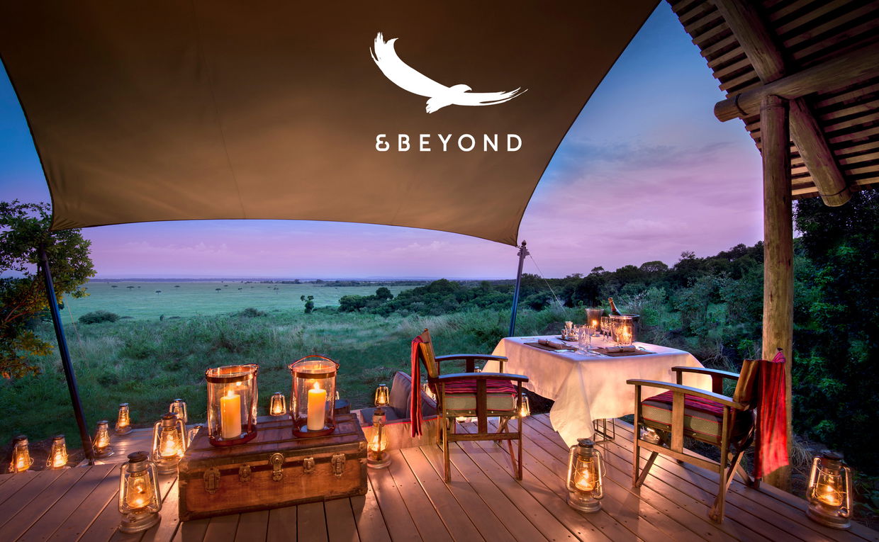 dinner setting on deck of suite at night by andbeyond Bateleur camp Kenia Mara with logo overlay dinner setting on deck of suite at night by andbeyond Bateleur camp Kenia Mara with logo overlay