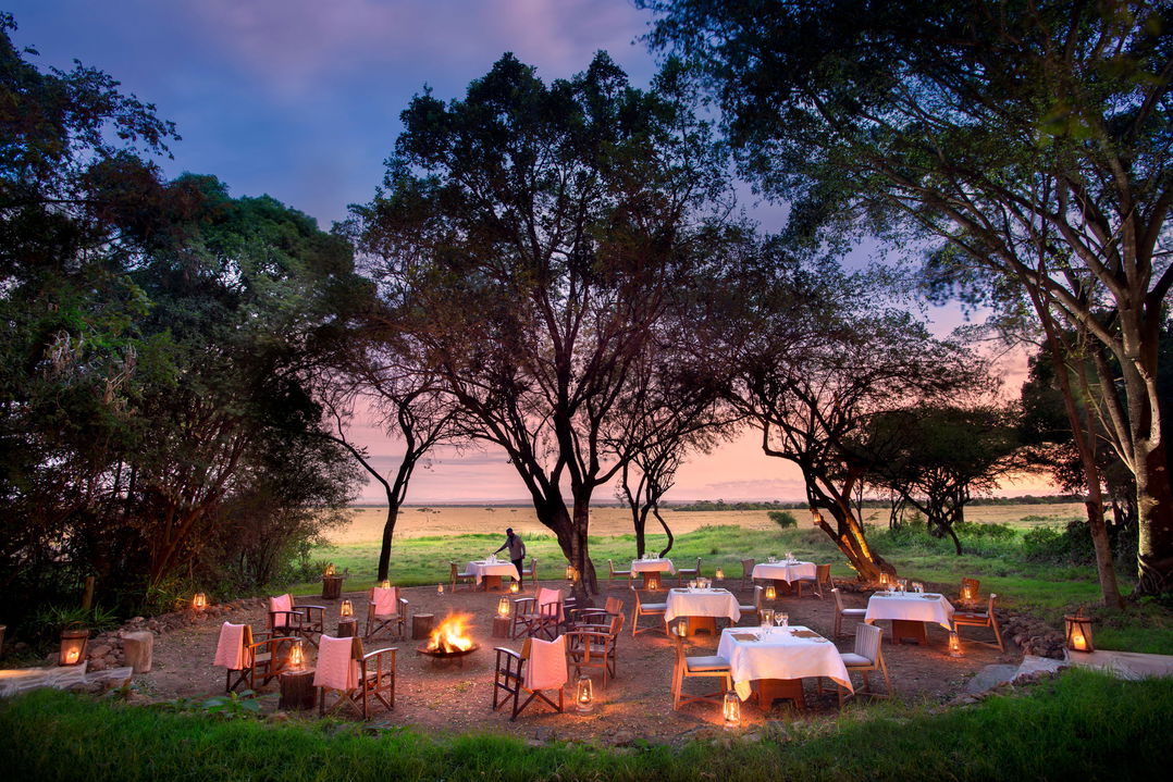 bush dinner setting under trees at night by andbeyond Bateleur camp Kenya Masai Mara