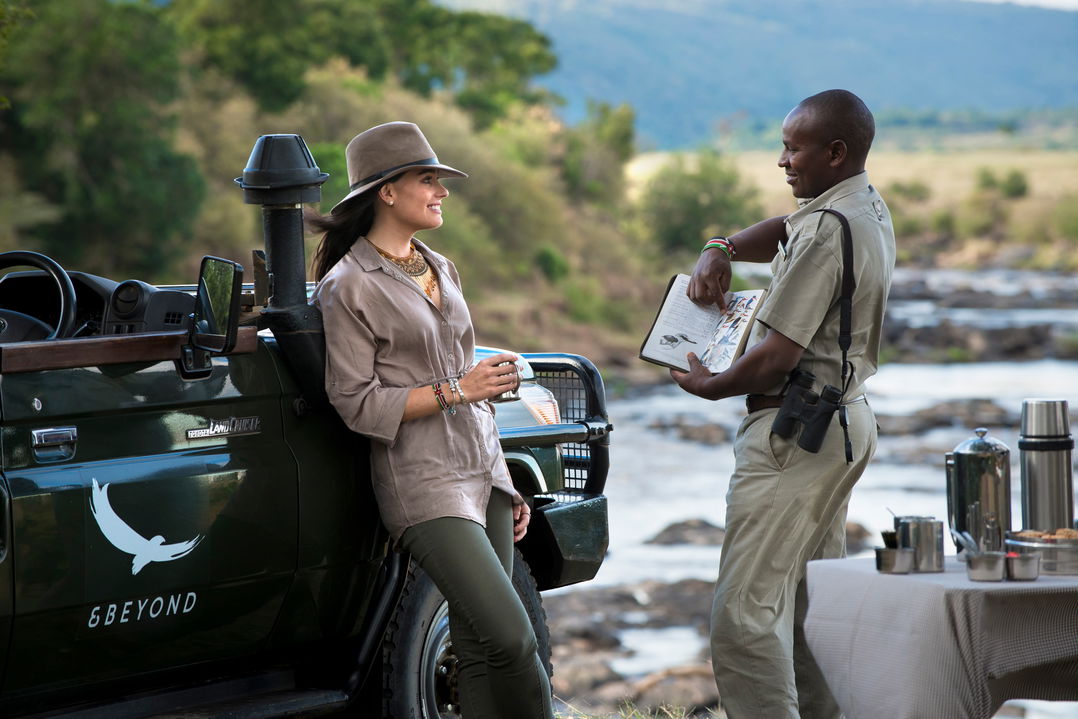 lady guest and guide talking by river near andbeyond Bateleur camp Kenya Masai Mara