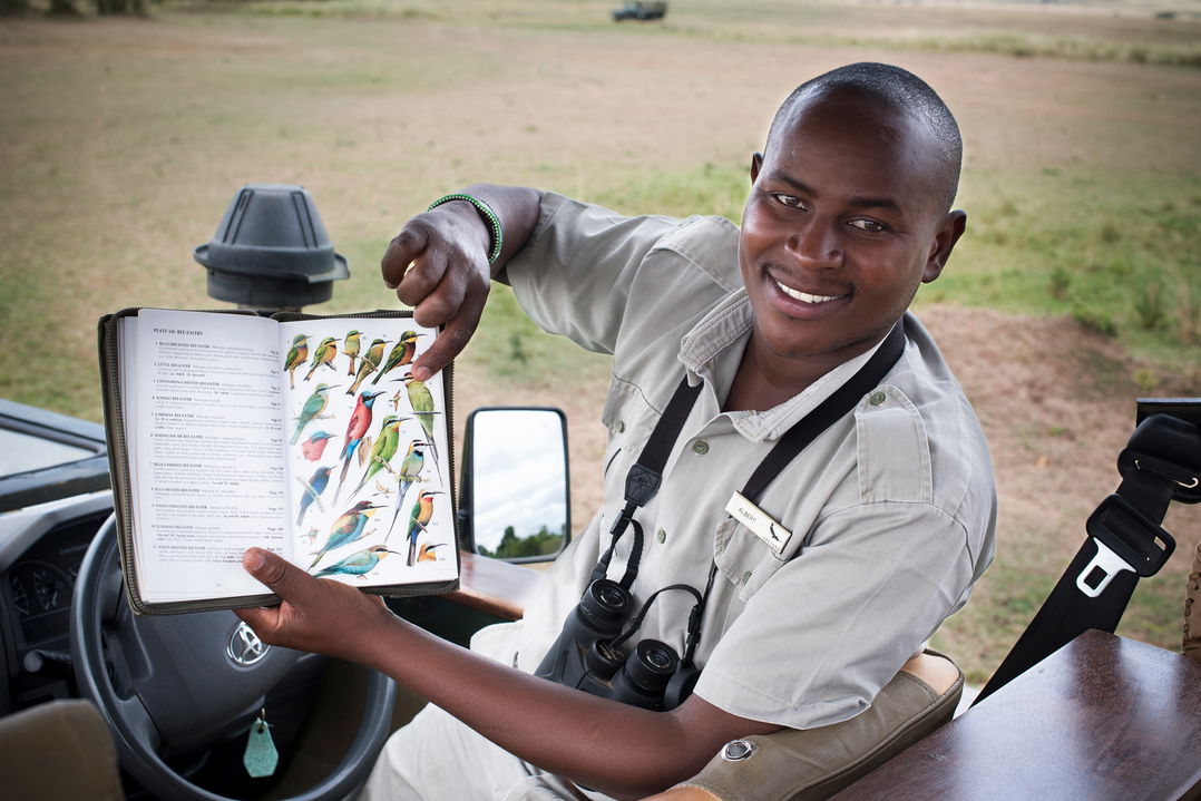 guide showing birding book to guests of andbeyond Bateleur camp Kenya Masai Mara
