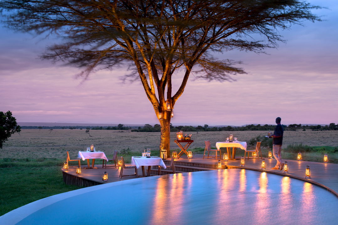 tables set for outside dinner by pool of andbeyond Bateleur camp Kenya Masai Mara
